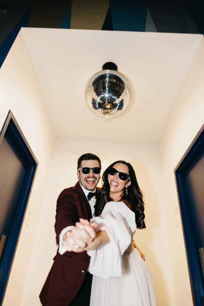 bride and groom posing under disco ball in Atlanta GA