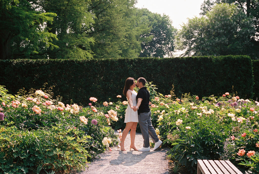 couple holding hands and kissing in the middle of flowers
