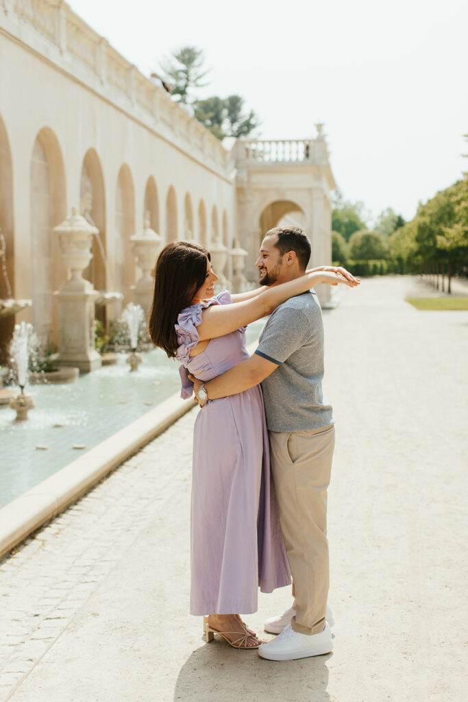 couple wrapping arms around each other in front of longwood gardens