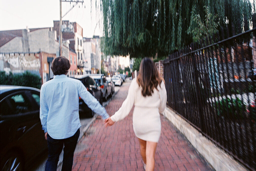 couple walking and holding hands blurry outfit photos
