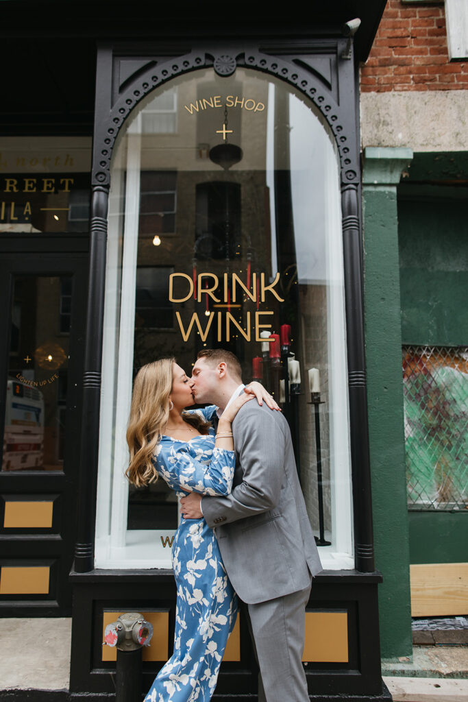 couple kissing in front of wine shop
