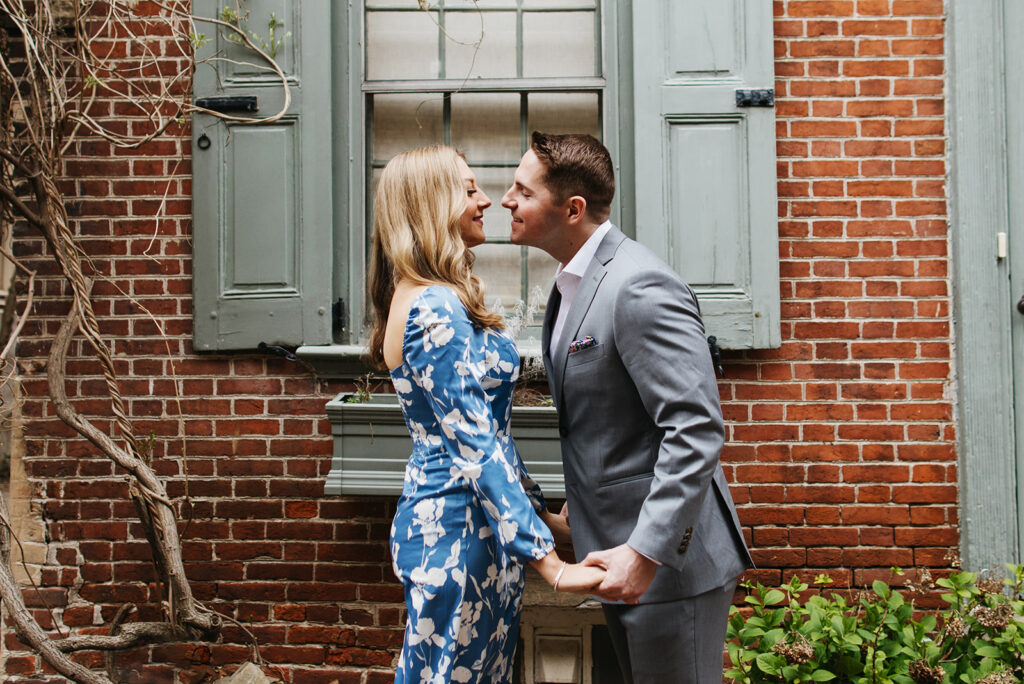 couple holding hands and smiling in front of brick building