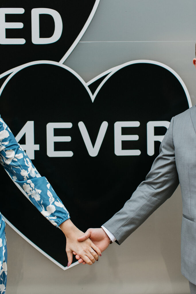 couple holding hands in front of building sign for philly engagement pictures