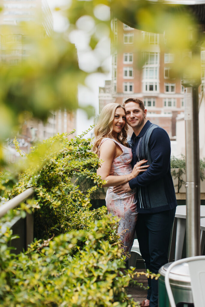 couple smiling and hugging in front of greenery in philly