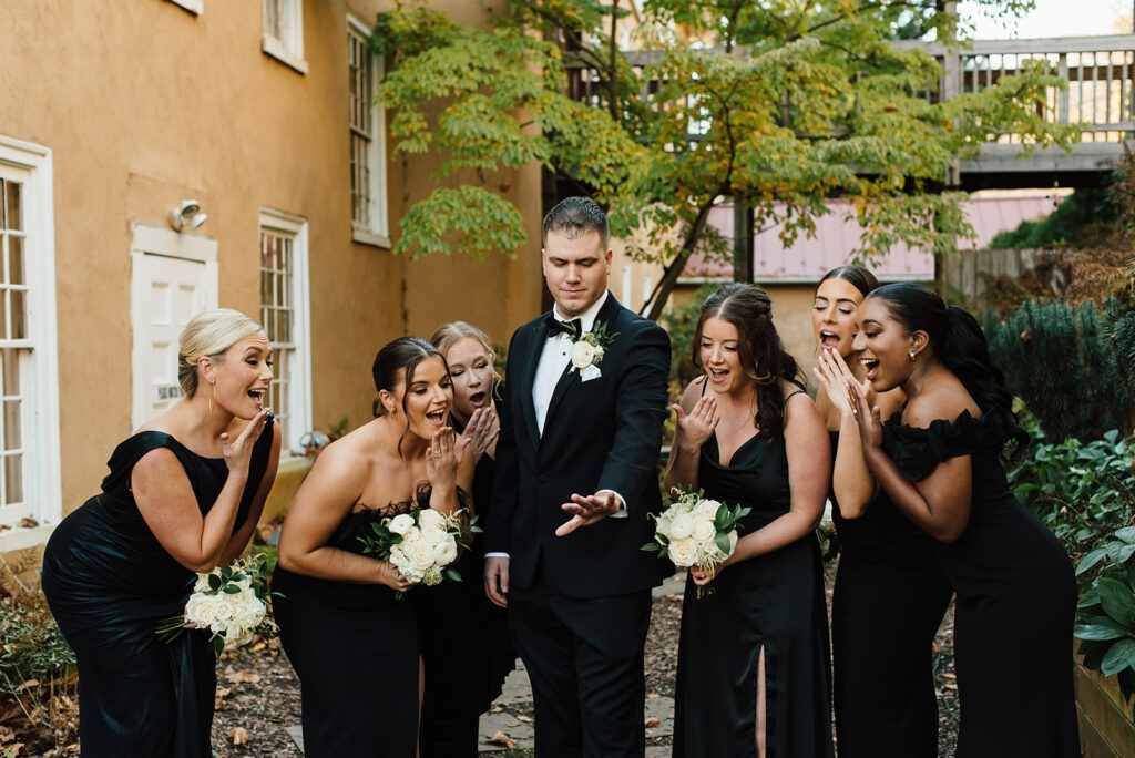black bridesmaid dresses with groom candid looking at ring photo